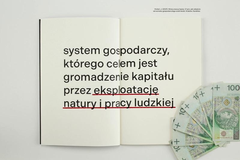 Klatka z filmu. Otwarta książka z napisem: System gostpodarczy którego celem jest gromadzenie kapitału przez eksploatację natury i pracy ludzkiej. Obok leży kilka banknotów stuzłotowych 