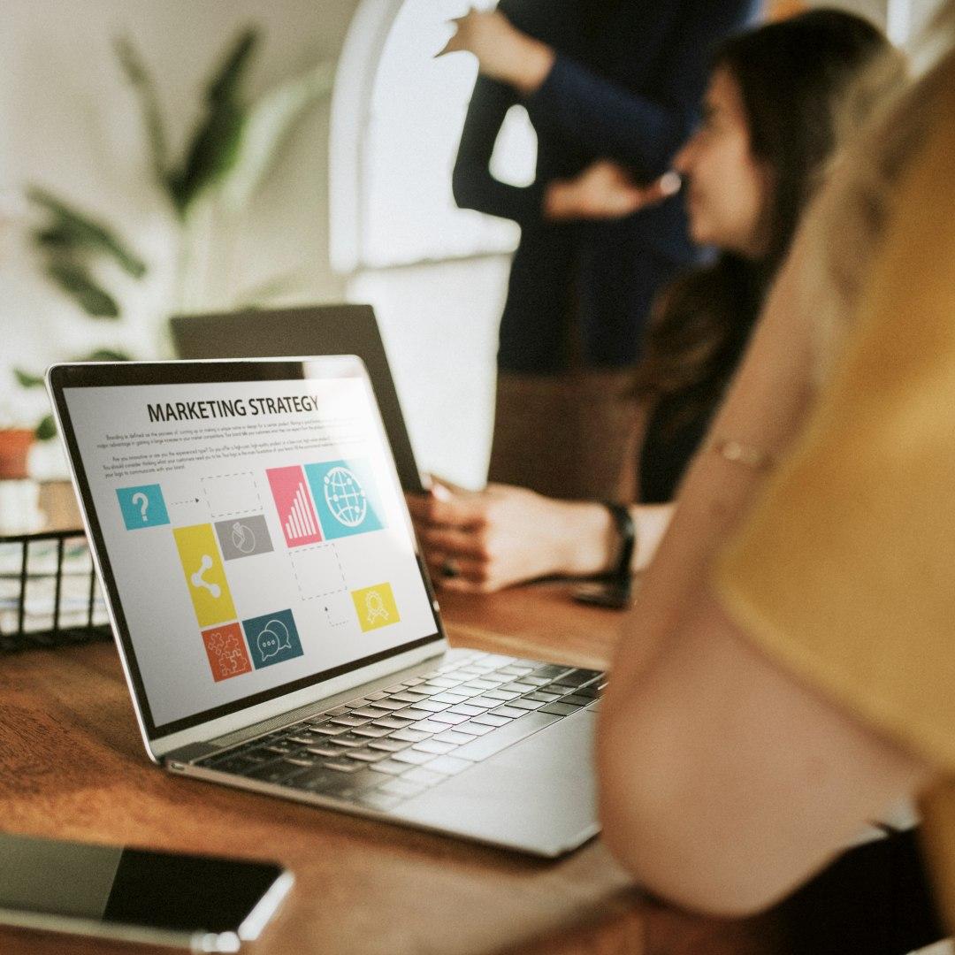 Zespół analizuje strategię marketingową z ikonami na ekranie laptopa.