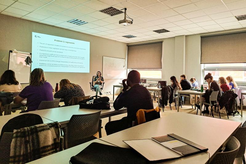 Studenci w klasie słuchają prezentacji wykładowczyni