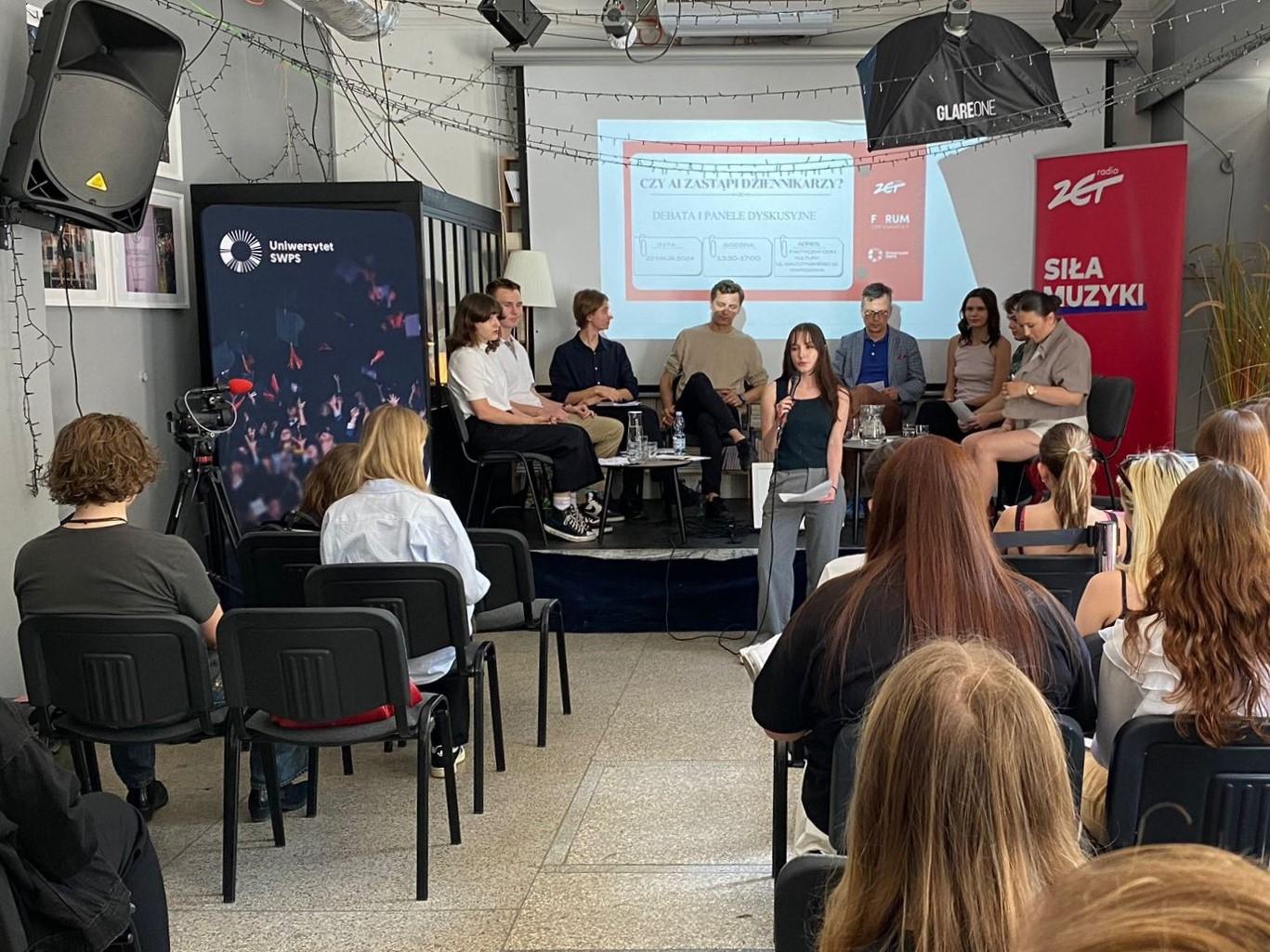 Debata oksfordzka podczas II Forum Dziennikarskiego. Uczestnicy siedzą na krzesłach na scenie, na pierwszym planie publiczność.