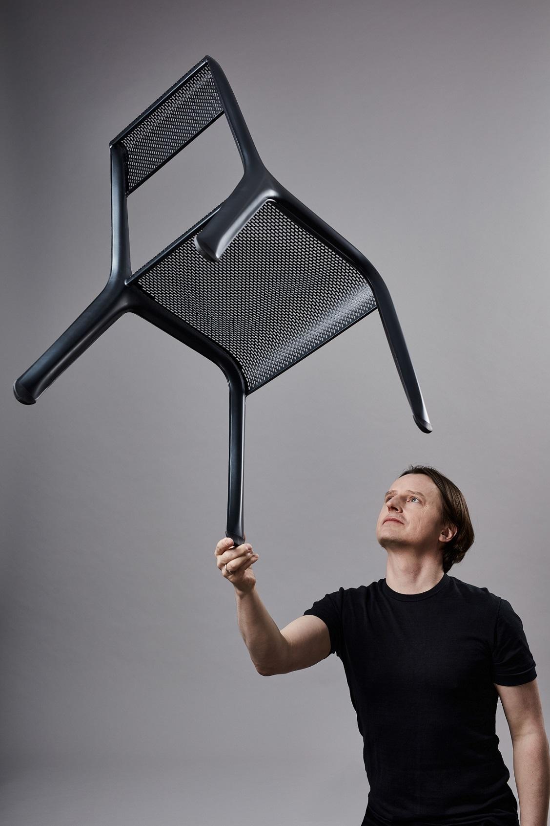Oskar Zięta trzymający zaprojektowane przez siebie krzesło Ultraleggera