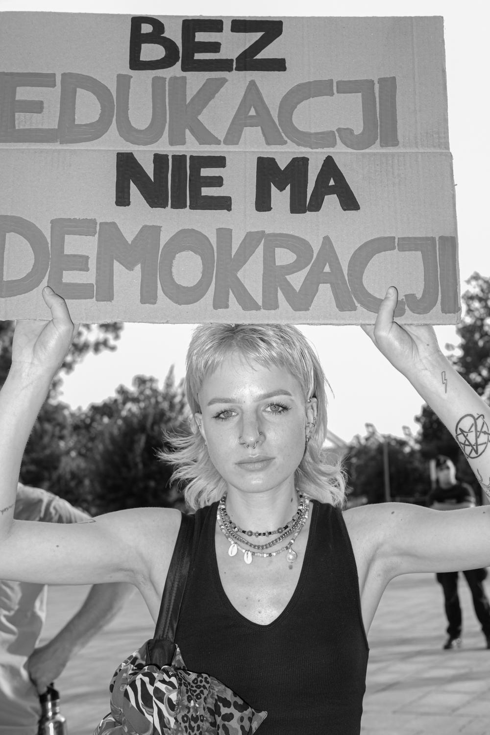 Dziewczyna trzyma transparent z napisem: Nie ma edukacji bez demokracji