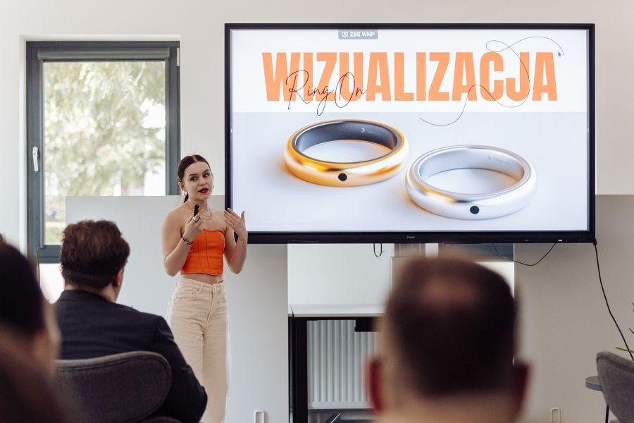 Dziewczyna wygłasza prezentację, w tle slajd z wizualizacją pierścionka RingOn
