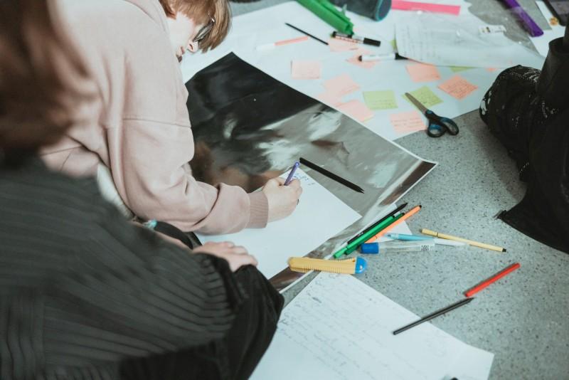 Sylwetki studentek na tle wyświetlanej prezentacji o tytule: Dzień dobry z grafiką
