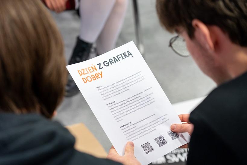 Uczeń trzymający w rękach ulotkę z napisem: dzień dobry z grafiką