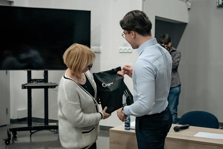 Monika Lewandowicz-Machnikowska wręcza torbę z logiem SWPS laureatowi konkursu