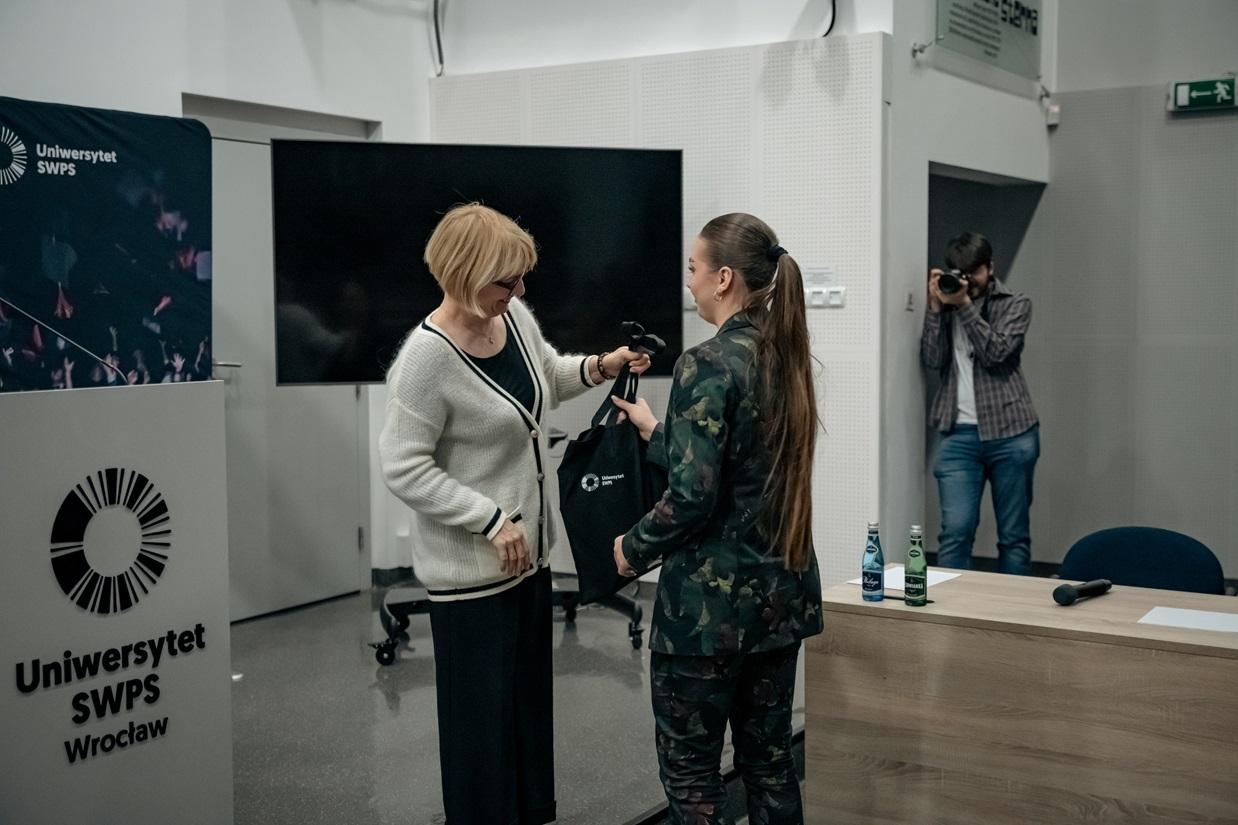Monika Lewandowicz-Machnikowska wręcza torbę z logiem SWPS laureatce konkursu