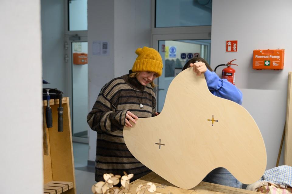 Dwie studentki trzymające wykrojony kawałek sklejki o nieregularnym kształcie