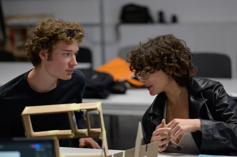 Student i studentka rozmawiający ze sobą siedząc przy stole