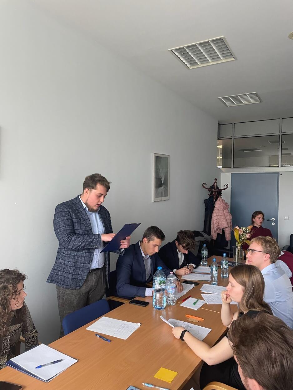 Grupa studentów siedzi przy stole i robi notatki podczas warsztatów.