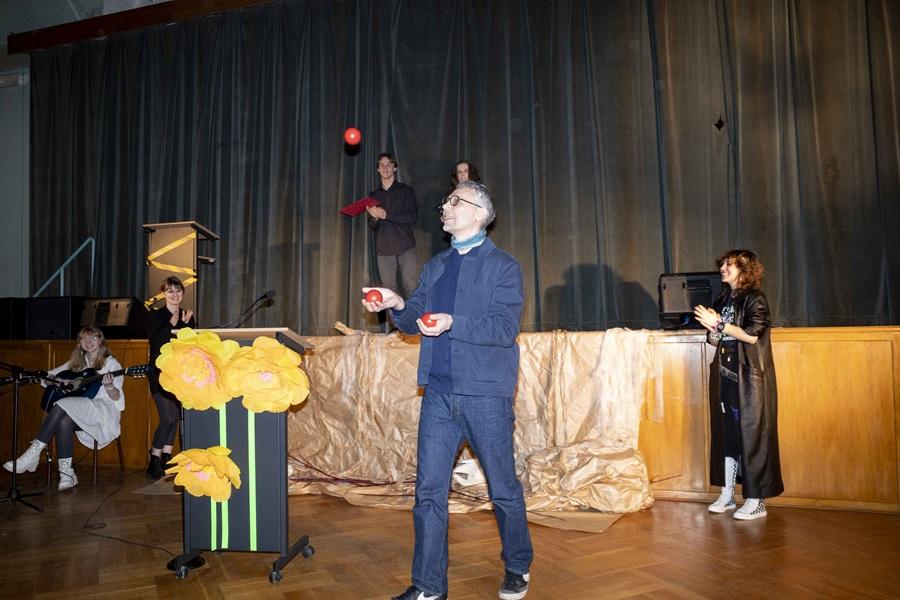 Michał Jakubowicz żonglujący czerwonymi piłkami przy mównicy