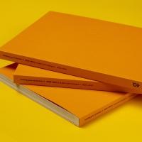 Stos katalogów prac studenckich stworzonych na kierunku grafika na Uniwersytecie SWSP