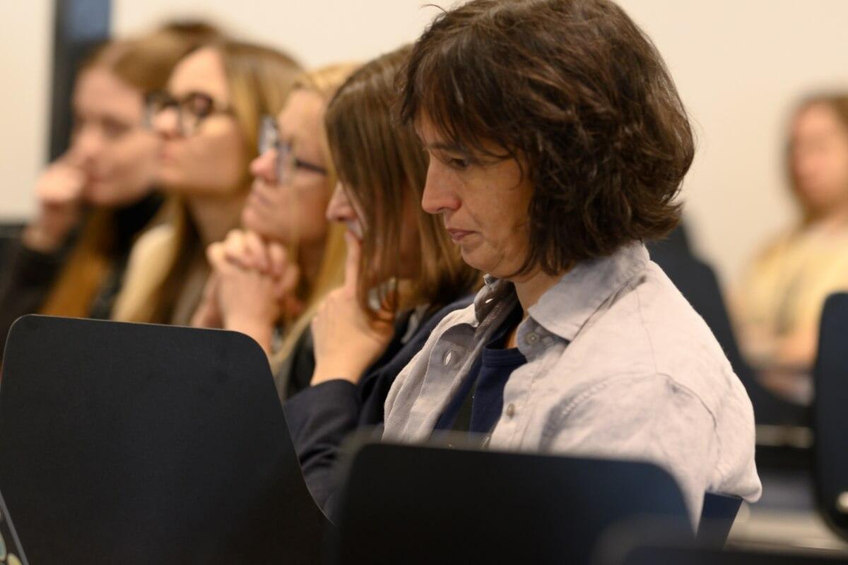 Pięć kobiet siedzi w rzędzie i przysłuchuje się konferencji "Innowacje społeczne. Wyzwania-rozwiązania-praktyki" na Uniwersytecie SWPS
