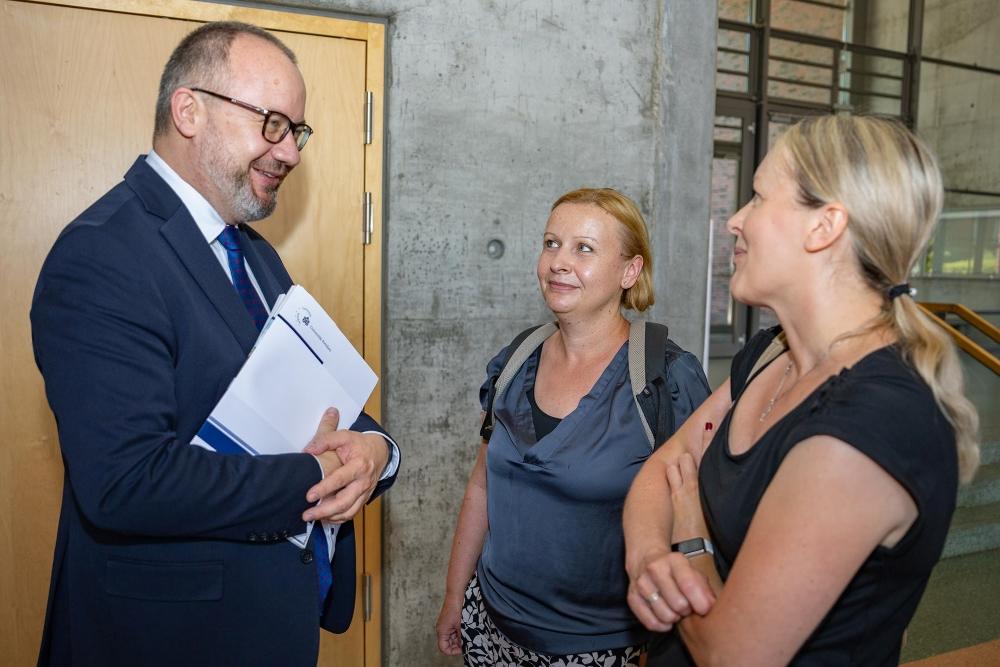 Adam Bodnar rozmawia z uczestniczkami uroczystości, w ręku trzyma dyplom