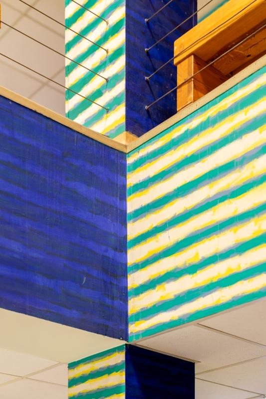Mural Leona Tarasewicza na całych ścianach wewnątrz budynku Uniwersytetu SWPS; poziome pasy w kontrastujących kolorach