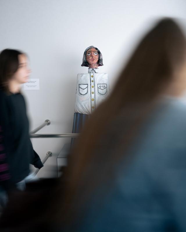 Rzeźba Uczennica autorstwa Si On widoczna zza sylwetek przechodzących studentek